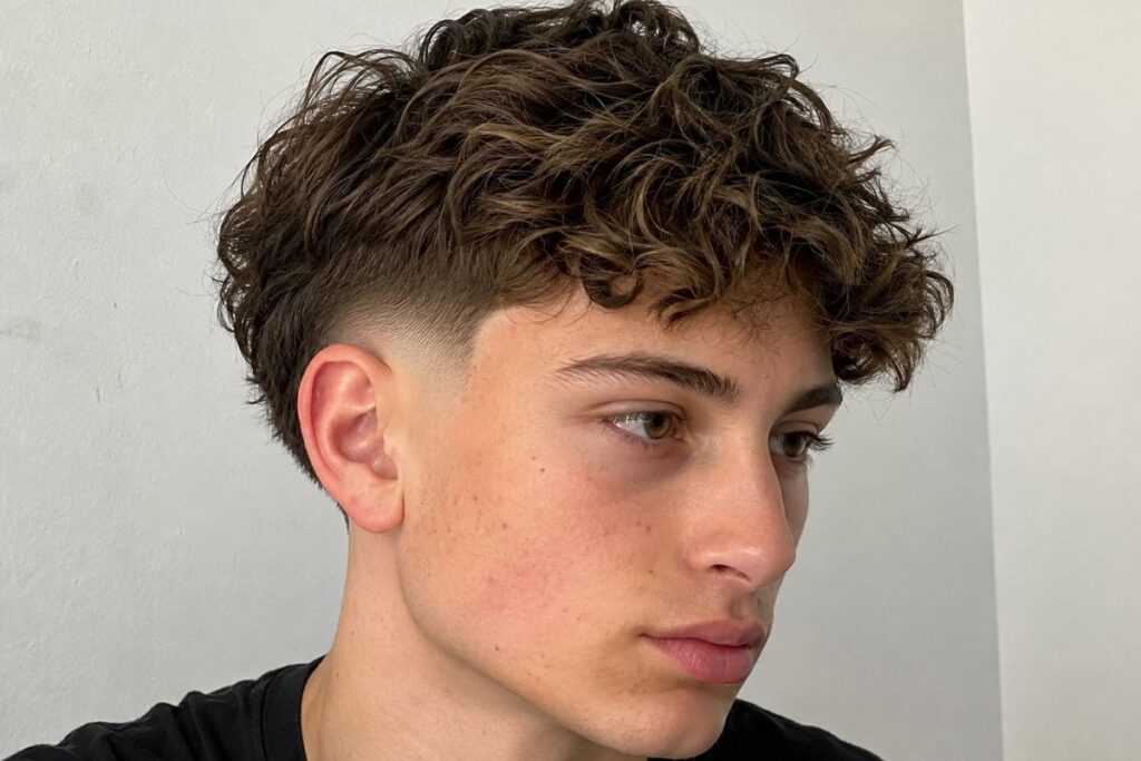 Burst fade haircut for teen boys with wavy hair and fuller textured top