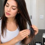 Woman applying coconut oil to hair roots for hair growth
