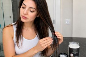 Woman applying coconut oil to hair roots for hair growth