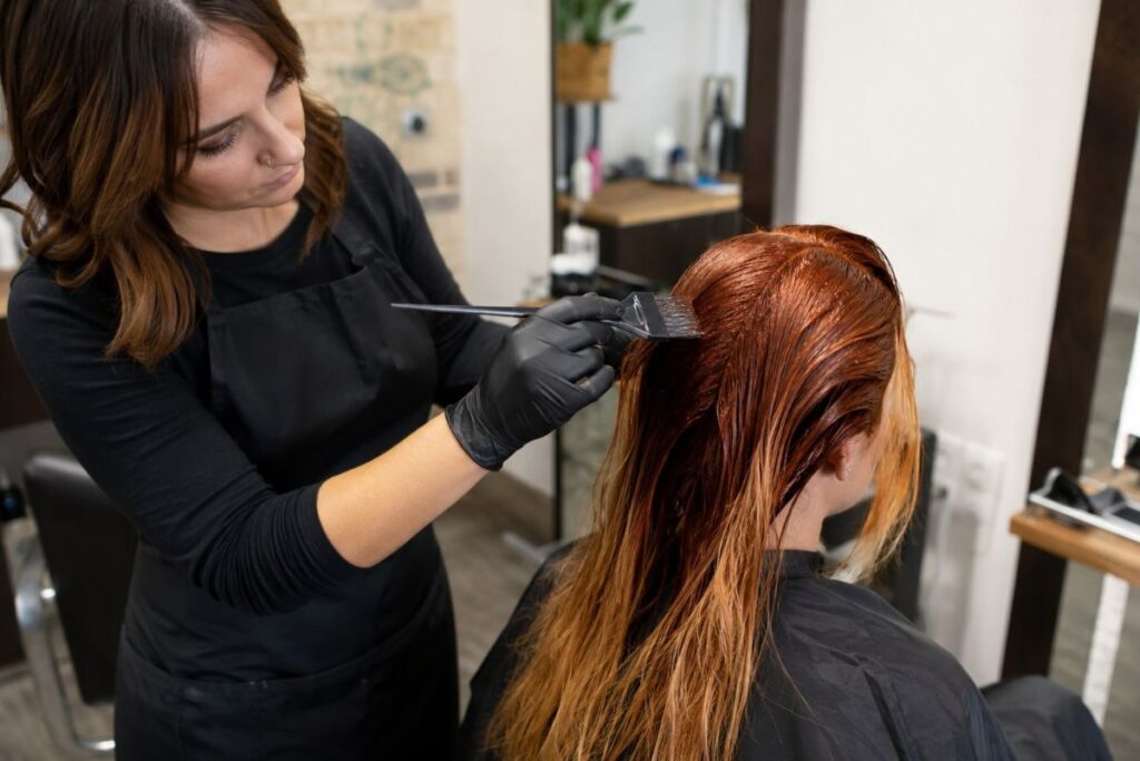 Colorist applying red hair color at a salon
