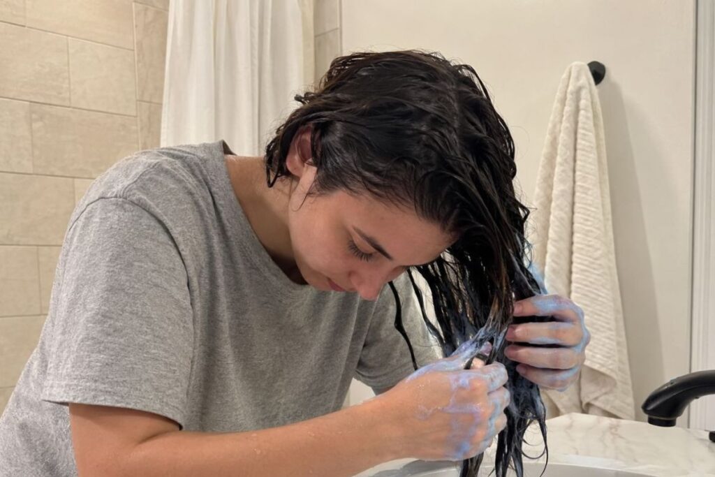 Applying blue shampoo to wet brunette hair

