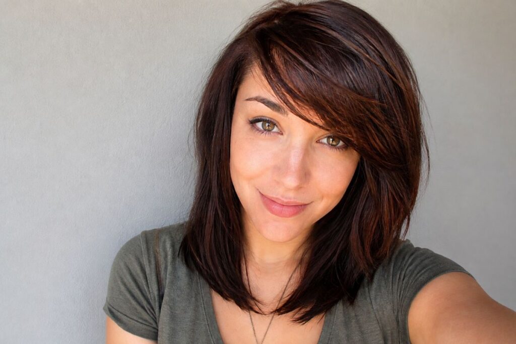 Medium layered cut with side swept bangs for heart face shape